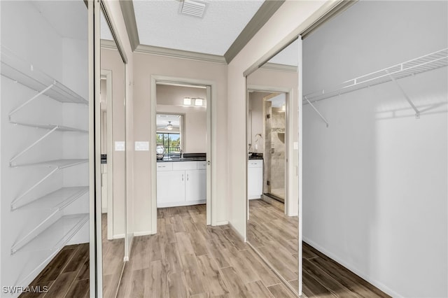 interior space featuring light hardwood / wood-style flooring, a textured ceiling, and ornamental molding