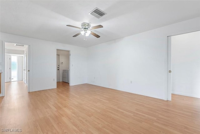 unfurnished room with light wood finished floors, visible vents, a ceiling fan, and independent washer and dryer