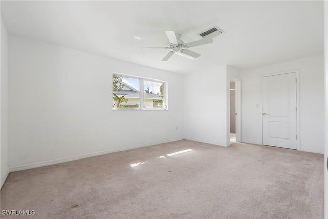 empty room with ceiling fan, carpet floors, visible vents, and baseboards