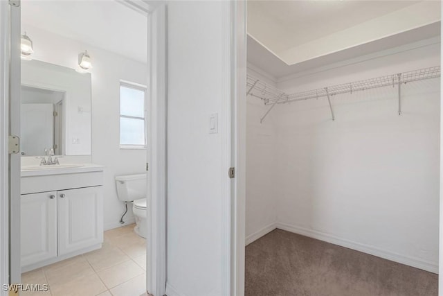 walk in closet featuring light tile patterned flooring and a sink