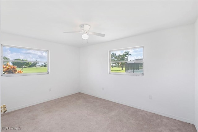 unfurnished room featuring light carpet, a ceiling fan, and baseboards