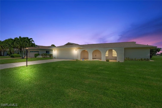 ranch-style home with an attached garage, a front lawn, concrete driveway, and stucco siding