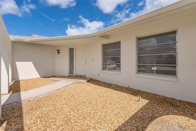 doorway to property featuring stucco siding