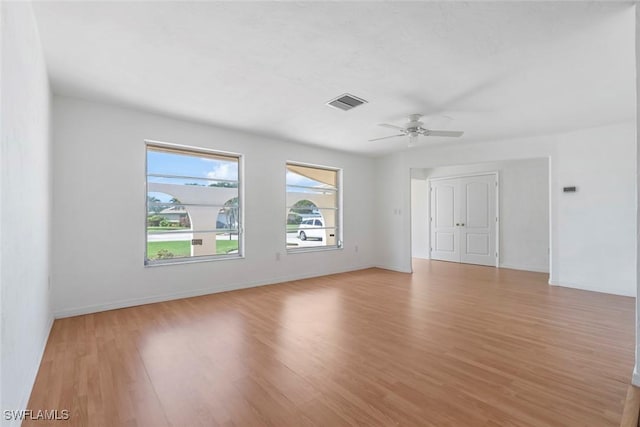 spare room featuring a ceiling fan, light wood-type flooring, visible vents, and baseboards