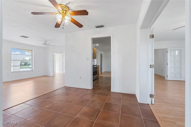 spare room featuring dark tile patterned flooring, visible vents, ceiling fan, and baseboards