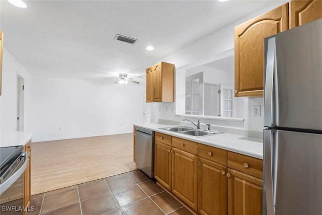 kitchen with ceiling fan, stainless steel appliances, dark tile patterned floors, a sink, and light countertops