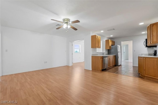 kitchen featuring light countertops, light wood finished floors, a ceiling fan, and appliances with stainless steel finishes