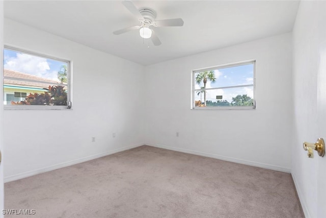 empty room featuring light carpet, a ceiling fan, and baseboards