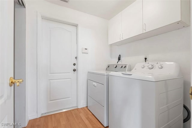 laundry area with cabinet space, light wood-style flooring, and separate washer and dryer