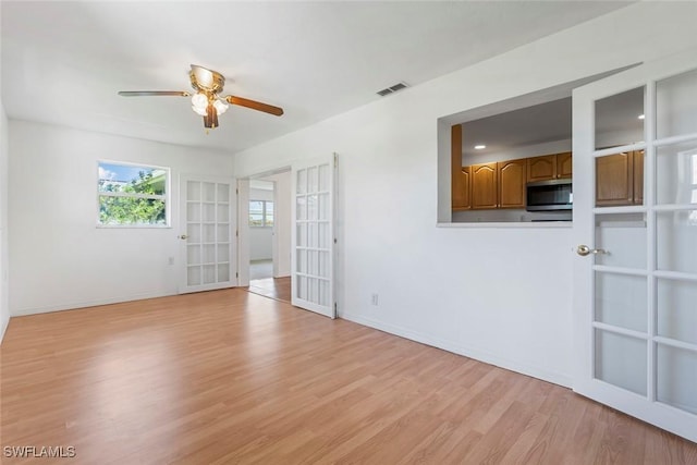 empty room with ceiling fan, light wood-style flooring, visible vents, and baseboards