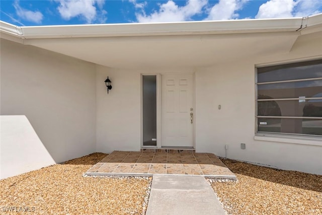 doorway to property featuring stucco siding