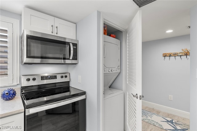 1401 Middle Gulf Dr Unit 301N, Sanibel, FL 33957 - kitchen featuring white cabinetry, stacked washer and clothes dryer, stainless steel appliances, baseboards, and visible vents