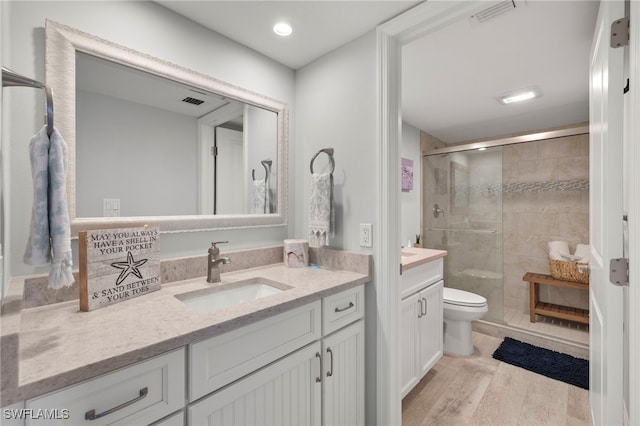 bathroom featuring a shower with shower door, vanity, and toilet