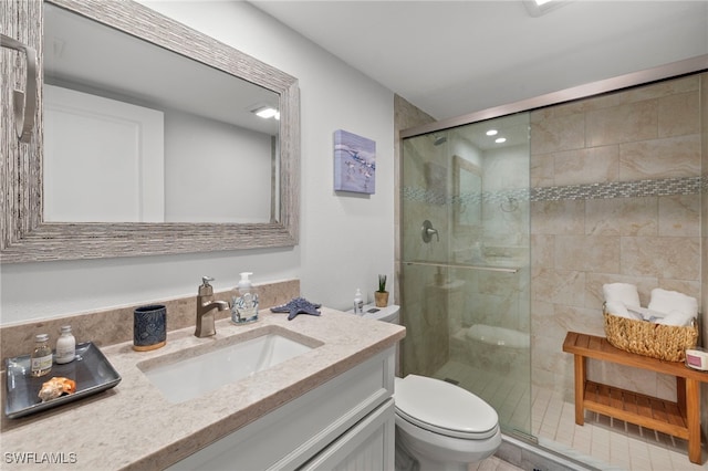 bathroom featuring a shower with shower door, vanity, tile patterned flooring, and toilet