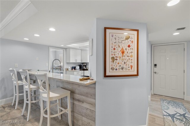 1401 Middle Gulf Dr Unit 301N, Sanibel, FL 33957 - kitchen with white cabinetry, recessed lighting, a sink, light wood finished floors, and visible vents