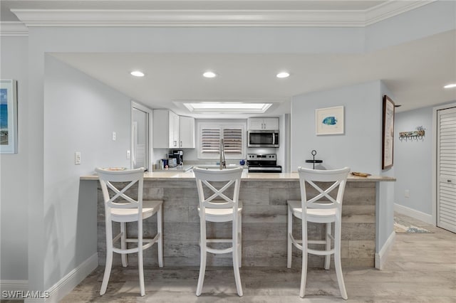 kitchen with crown molding, stove, light wood-type flooring, white cabinetry, and kitchen peninsula