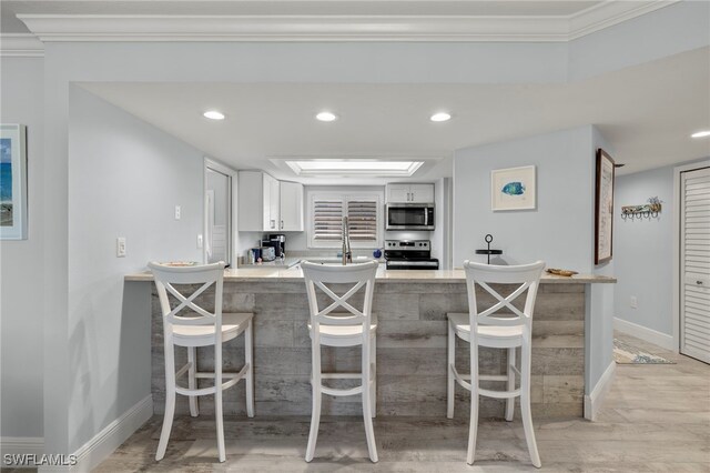 1401 Middle Gulf Dr Unit 301N, Sanibel, FL 33957 - kitchen with a breakfast bar, white cabinets, stainless steel appliances, and a peninsula