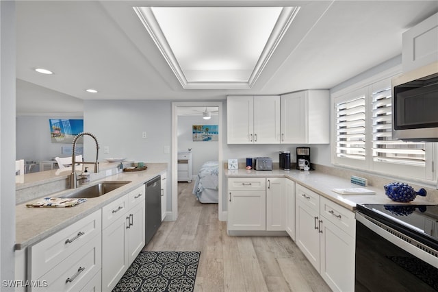 1401 Middle Gulf Dr Unit 301N, Sanibel, FL 33957 - kitchen featuring light wood-type flooring, stainless steel appliances, a raised ceiling, a sink, and white cabinets