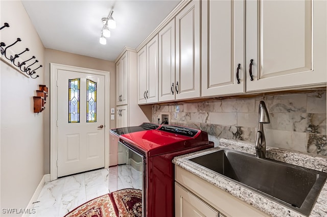 clothes washing area with sink, washer and clothes dryer, track lighting, and cabinets