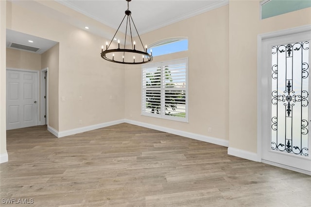 foyer with a notable chandelier, hardwood / wood-style floors, and crown molding