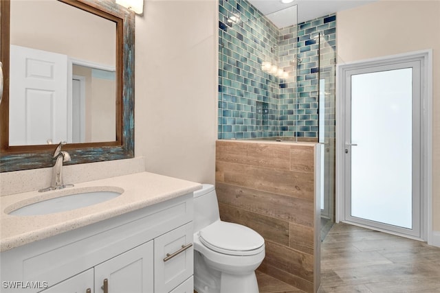 bathroom featuring toilet, vanity, and a shower with shower door