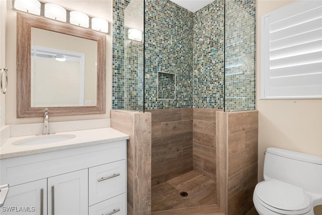 bathroom featuring tiled shower, vanity, and toilet