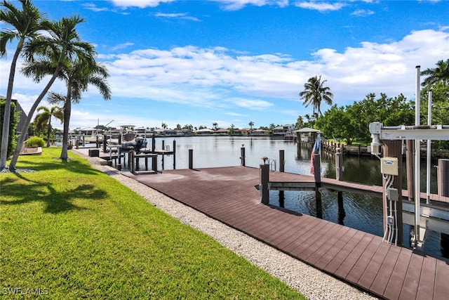 view of dock with a lawn and a water view