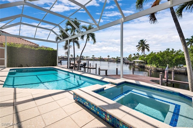 view of pool with glass enclosure, a patio, a water view, and an in ground hot tub