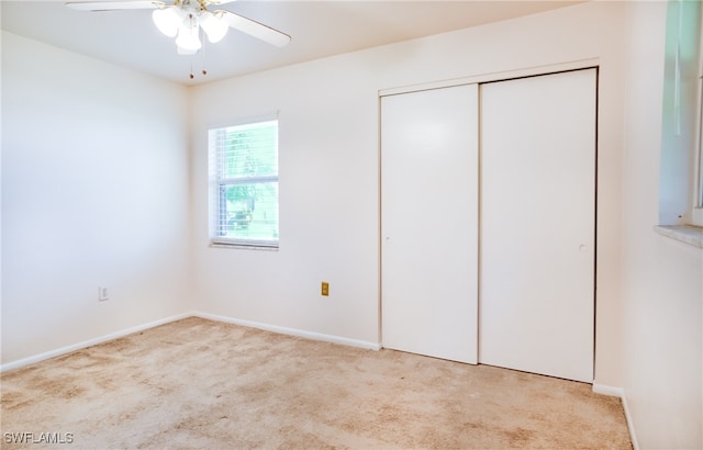 unfurnished bedroom featuring ceiling fan, light carpet, and a closet