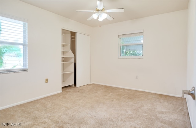 unfurnished bedroom with ceiling fan, light carpet, and a closet