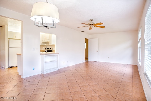 unfurnished living room featuring light tile patterned flooring and ceiling fan with notable chandelier