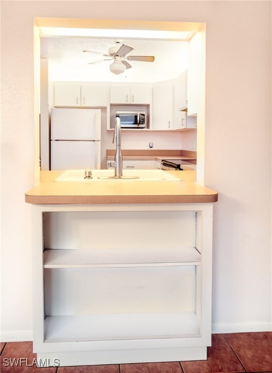 kitchen with white refrigerator, dark tile patterned flooring, and ceiling fan