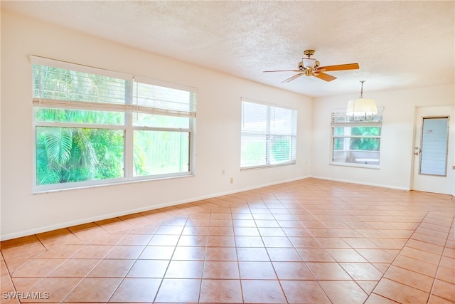 empty room featuring ceiling fan, light tile patterned flooring, and a textured ceiling