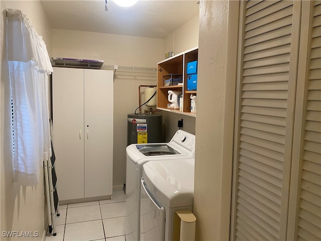 laundry room with washer and clothes dryer, water heater, cabinets, and light tile patterned floors