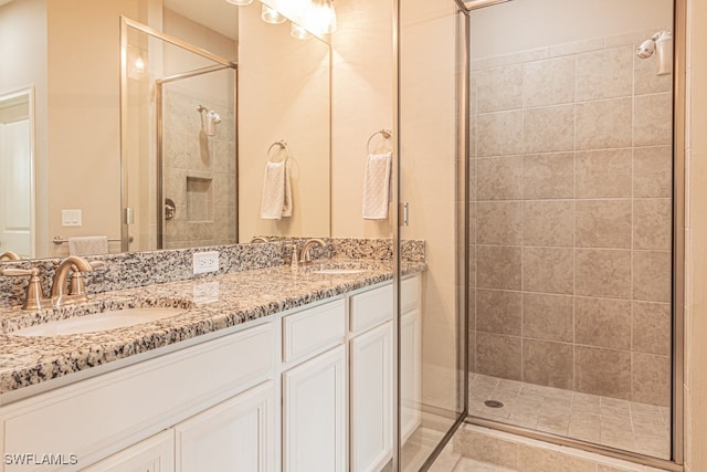 bathroom with a shower with shower door and double vanity