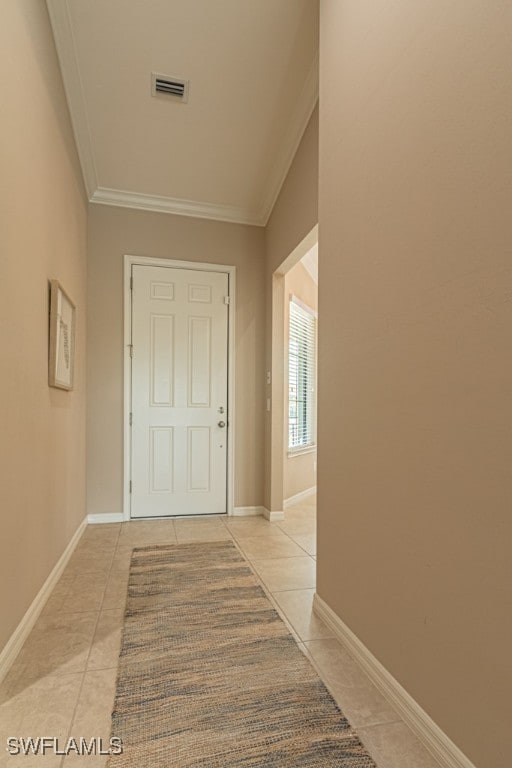 corridor featuring light tile patterned flooring, ornamental molding, and vaulted ceiling