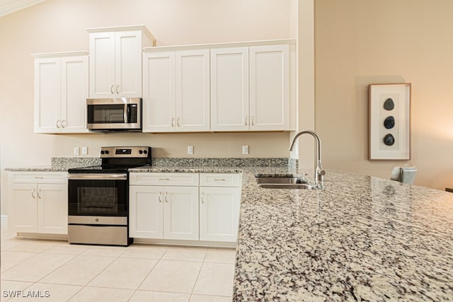 kitchen featuring light tile patterned flooring, appliances with stainless steel finishes, light stone countertops, white cabinetry, and sink