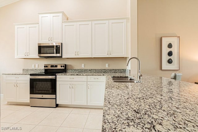 kitchen with a sink, light stone counters, light tile patterned floors, and stainless steel appliances