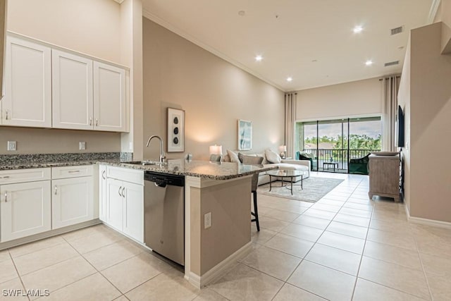 kitchen with a peninsula, open floor plan, a sink, dark stone countertops, and dishwasher