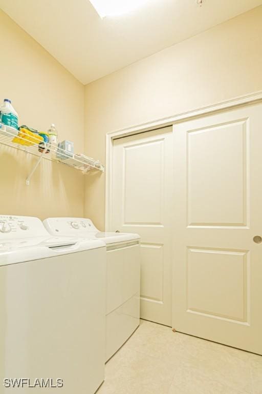 laundry area with laundry area, washer and clothes dryer, and light tile patterned floors