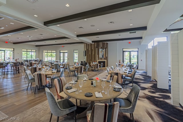 dining area featuring beamed ceiling, wood-type flooring, and a healthy amount of sunlight