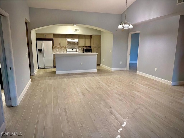 interior space featuring decorative backsplash, a chandelier, a center island, light wood-type flooring, and white appliances