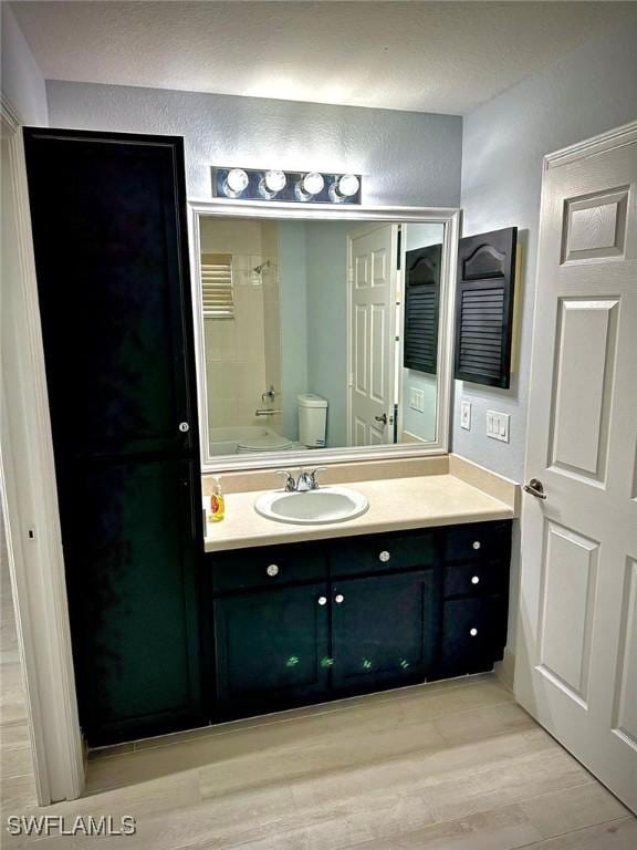 full bathroom featuring shower / bathtub combination, vanity, toilet, and hardwood / wood-style floors