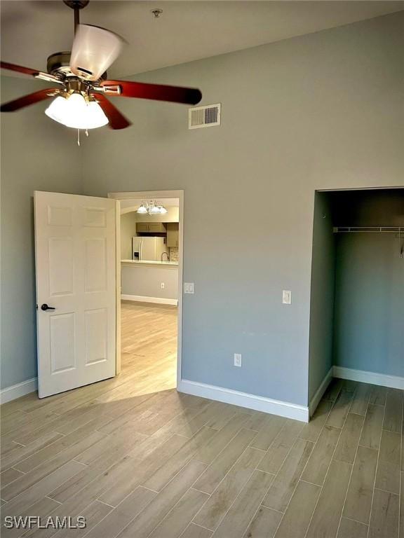 unfurnished bedroom featuring ceiling fan, fridge with ice dispenser, light hardwood / wood-style floors, and a closet