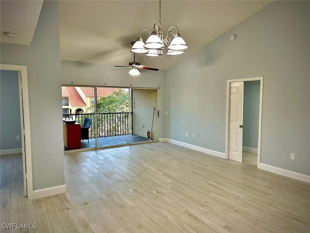 empty room with ceiling fan with notable chandelier, high vaulted ceiling, and light hardwood / wood-style floors