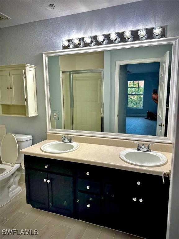 bathroom with an enclosed shower, vanity, and toilet