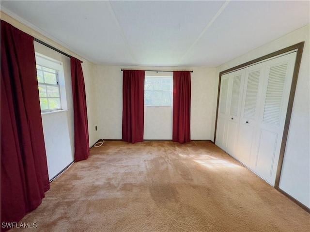 unfurnished bedroom with light colored carpet and a closet