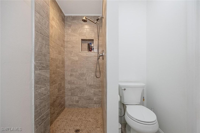 bathroom featuring a tile shower and toilet