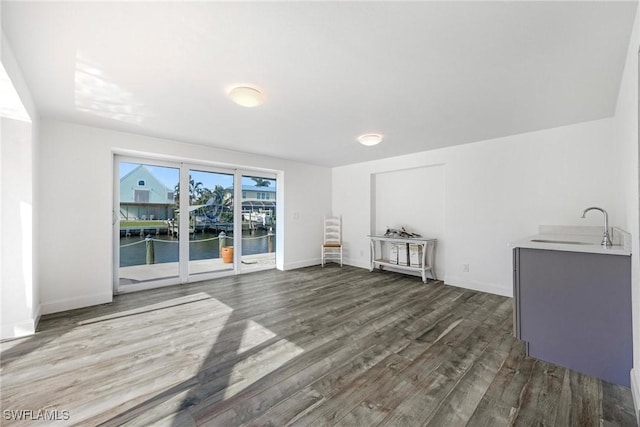 unfurnished living room with a water view, dark hardwood / wood-style floors, and sink