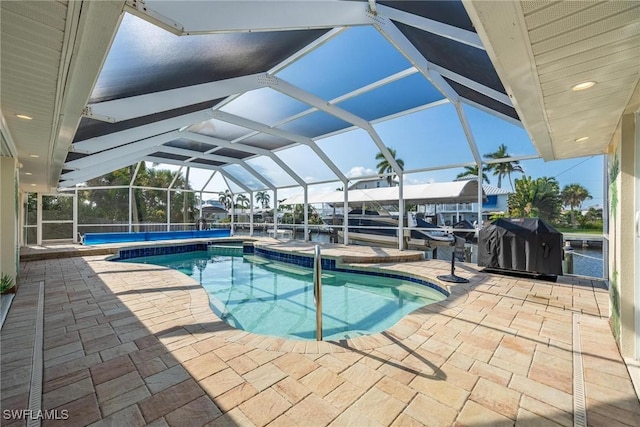 view of pool with glass enclosure, a patio, and grilling area